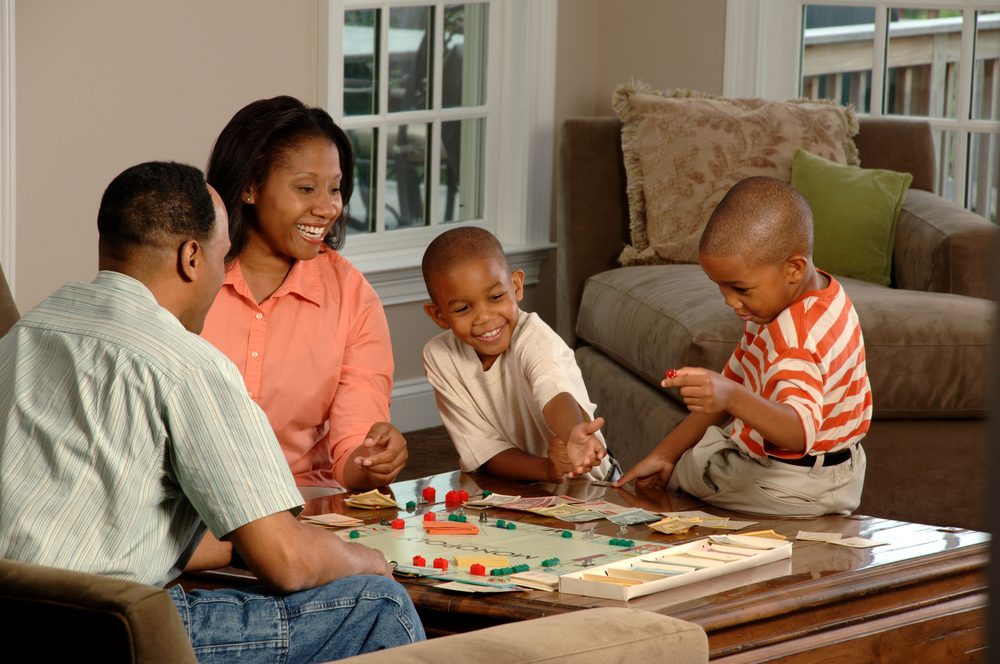 Family sitting around a table playing a board game together