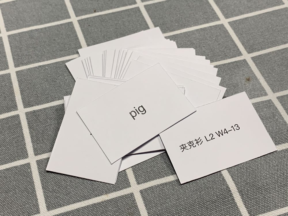 A hand holding paper flashcards used for language vocabulary practice