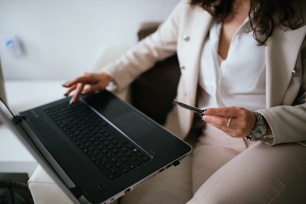 Woman holding a credit card while shopping online on a laptop at home