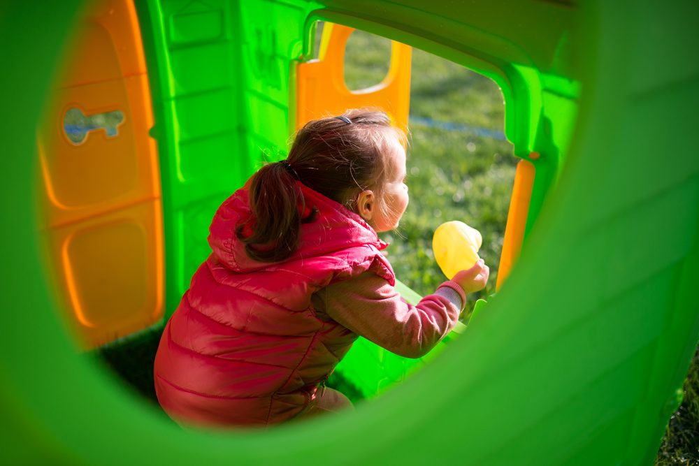 Child playing inside a colorful outdoor playhouse in a park