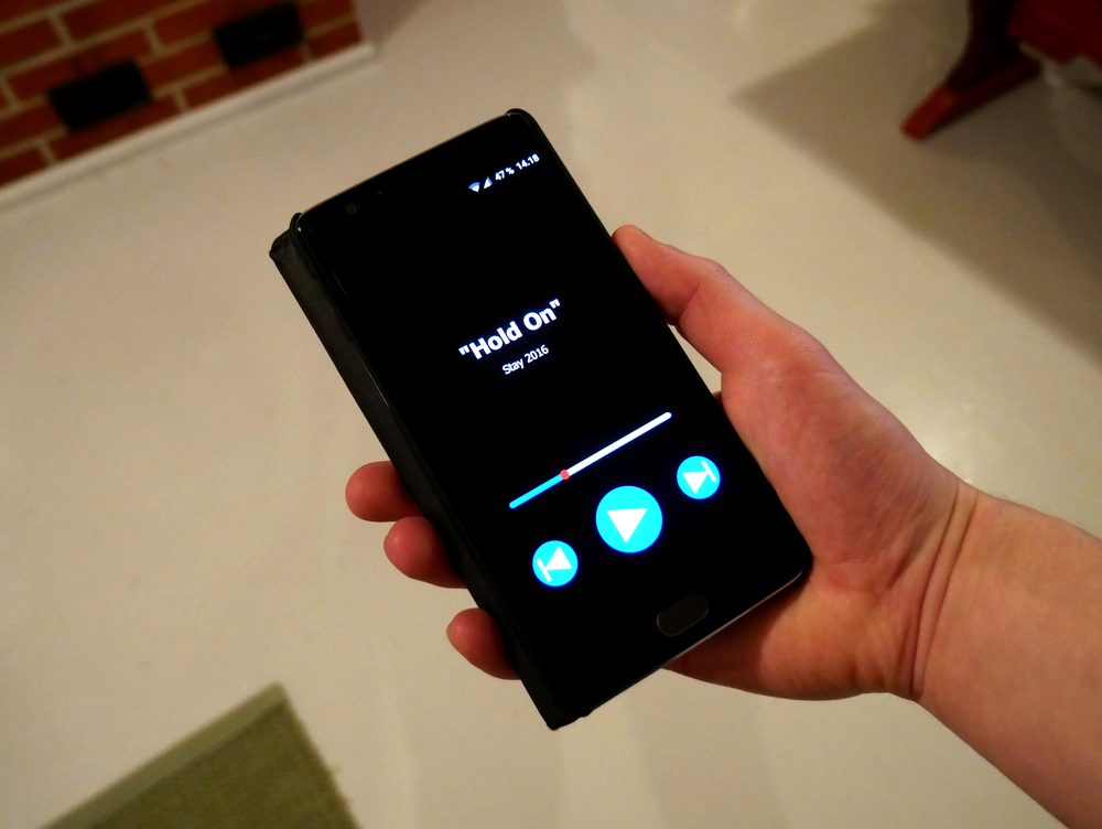Hand holding a smartphone with an app open, representing the short check-ins typical of idle games and language apps