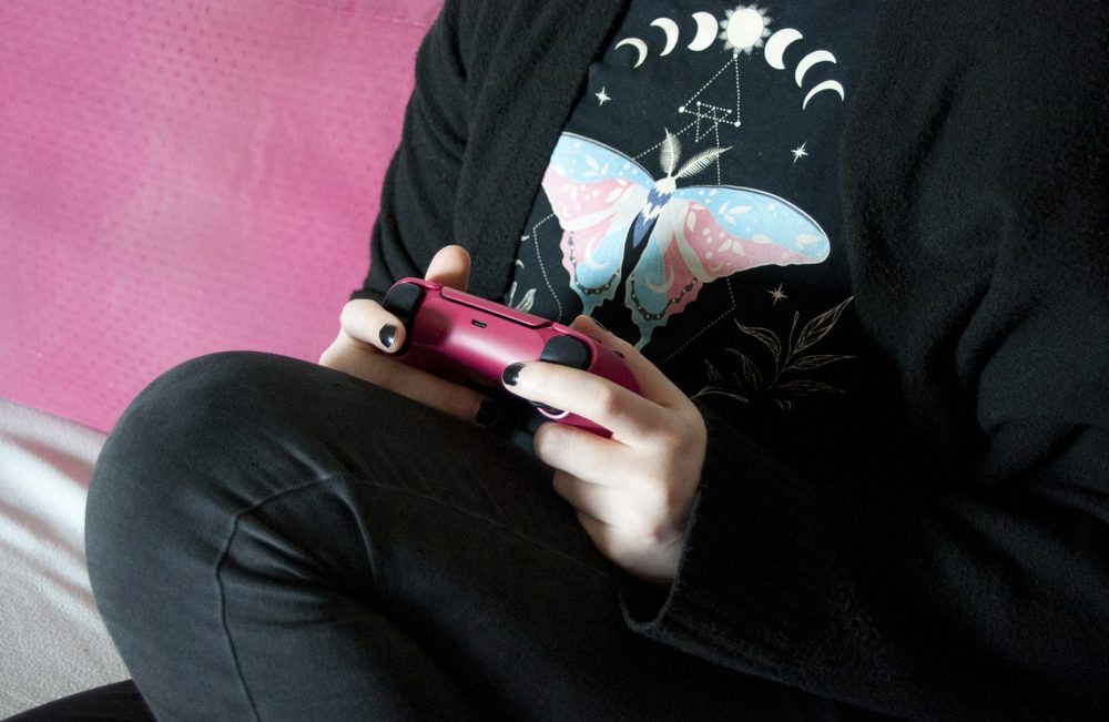 Person holding a game controller, representing language learning through games versus apps