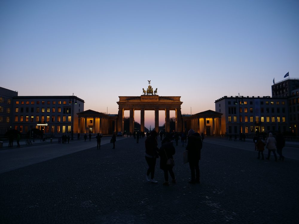 The Brandenburg Gate in Berlin at dusk with people walking across Pariser Platz
