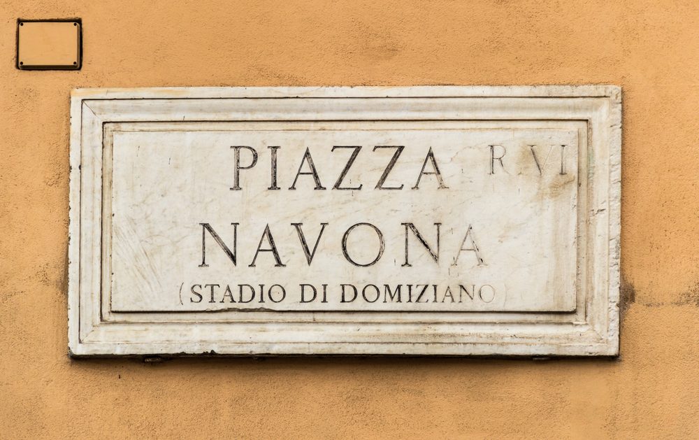 Marble street sign for Piazza Navona mounted on an ochre wall in Rome