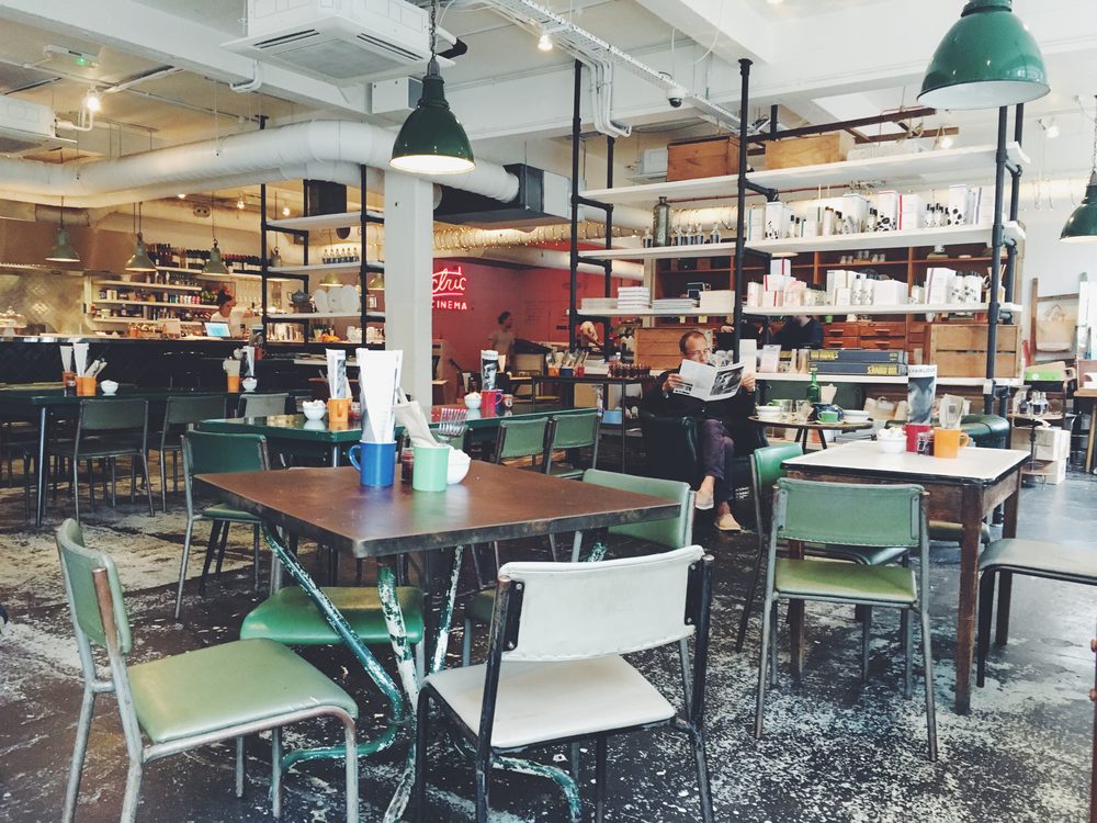 Person reading a newspaper alone at a cafe table