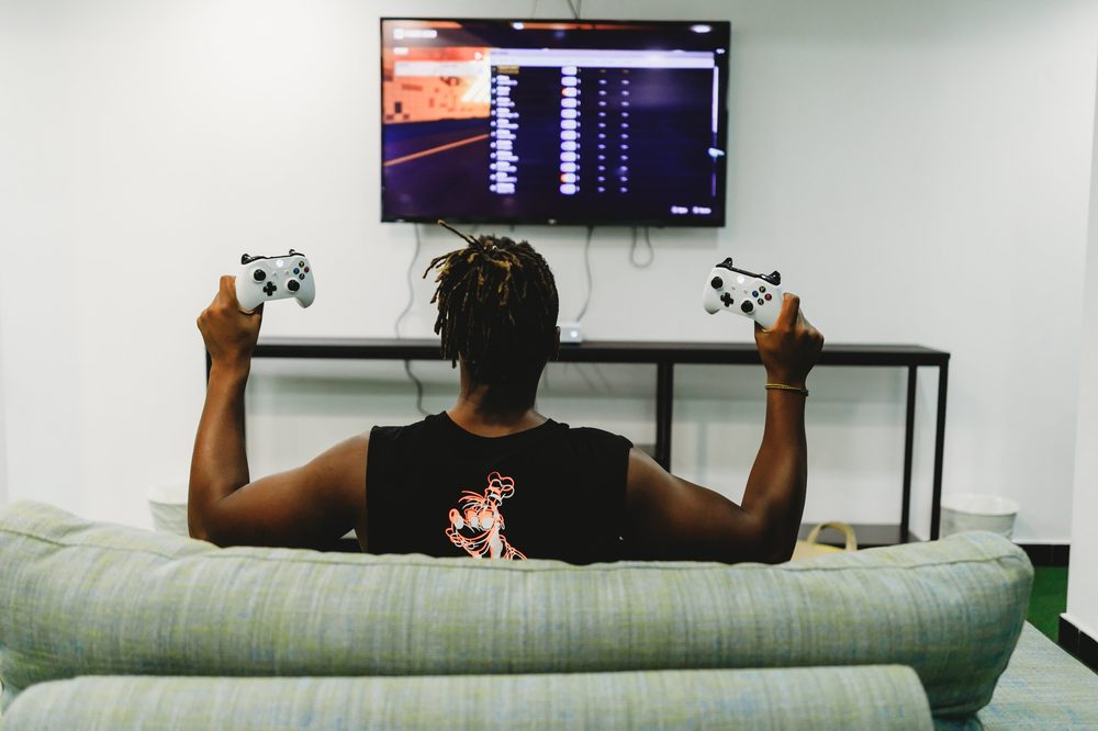 Man holding two game controllers while playing on his console, representing a gamer looking for a different way to learn a language