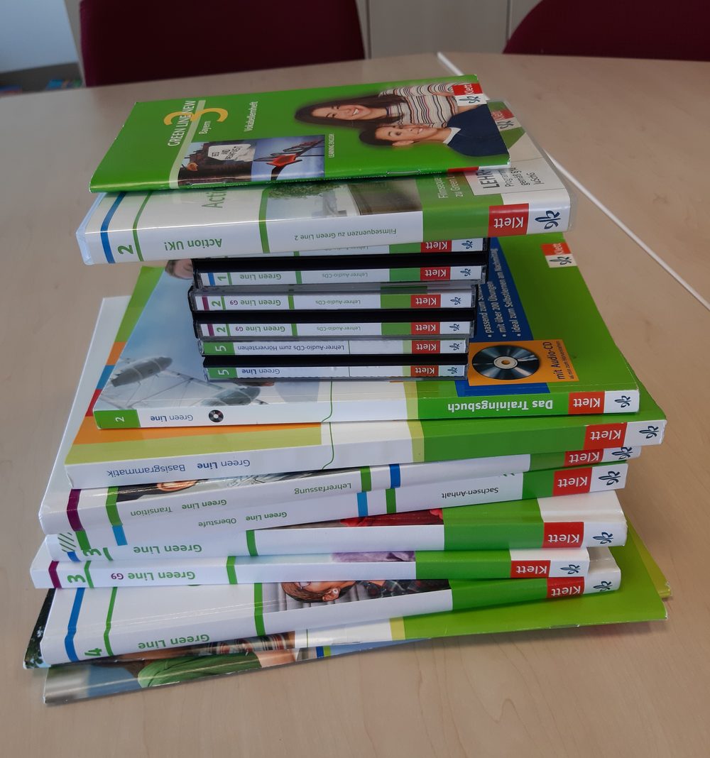 Stack of language learning textbooks and workbooks on a table